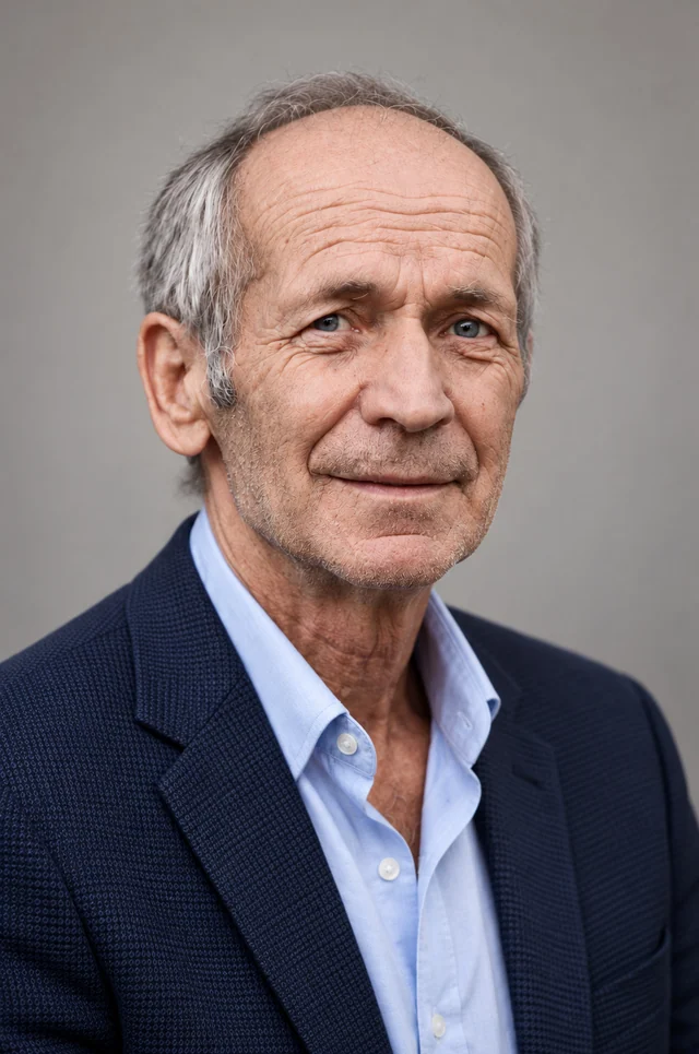 AI-generated professional headshot of the same older man with gray hair and visible facial lines, wearing a navy blazer and a light blue shirt against a gray background.